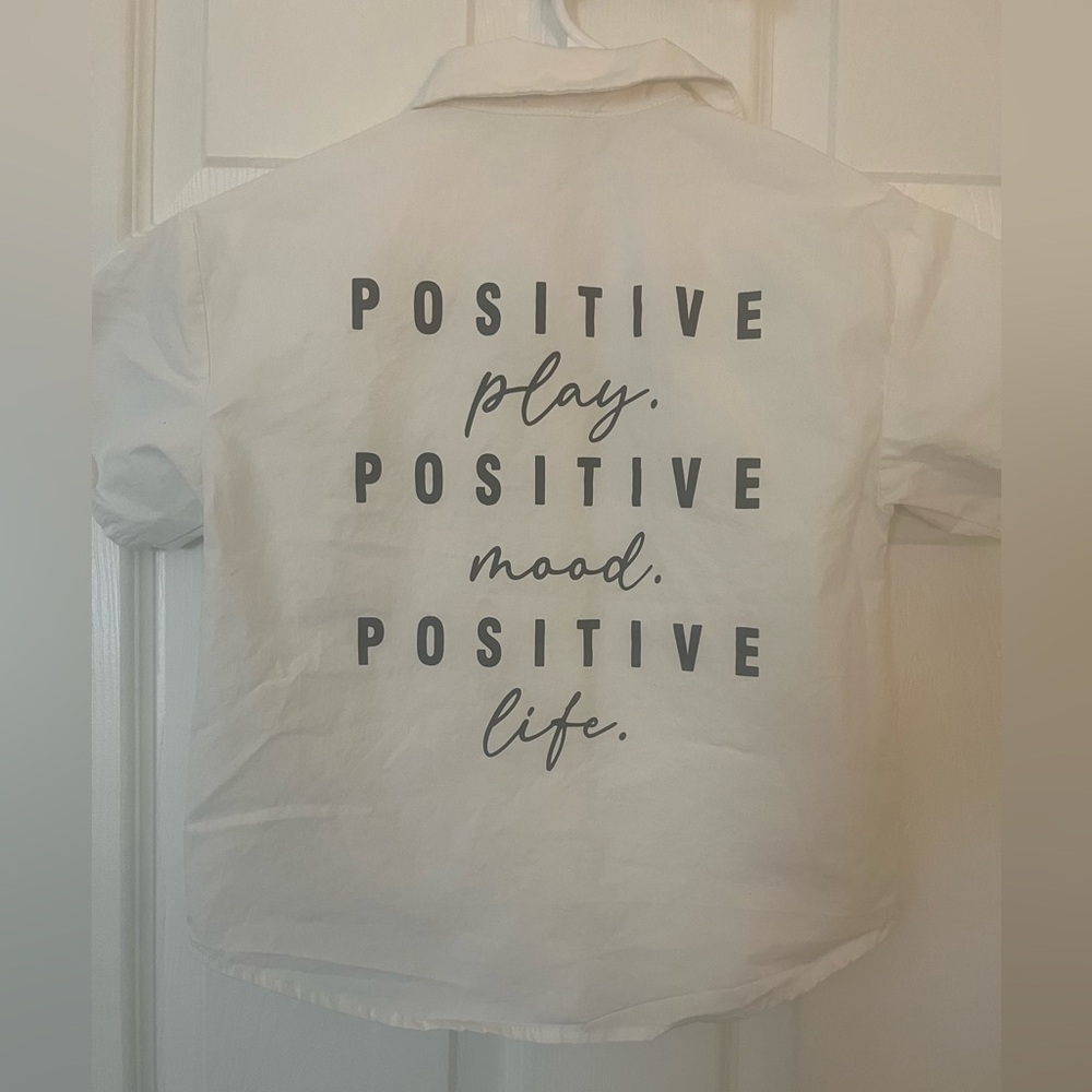 Kids size 5 white short sleeve‎ button down shirt with black lettering on back